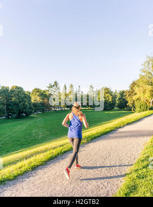 Giovane donna in abbigliamento sportivo a fare jogging nel parco, Monaco di Baviera, Baviera, Baviera, Germania Foto Stock