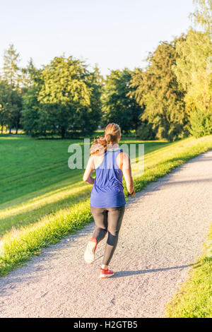 Giovane donna in abbigliamento sportivo a fare jogging nel parco, Monaco di Baviera, Baviera, Baviera, Germania Foto Stock