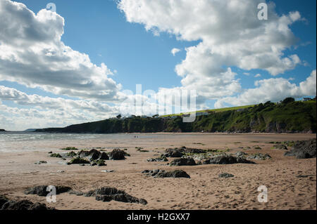 Bantham Beach, Devon, Regno Unito. Nuvole bianche riempiono un cielo blu in un giorno estivo sopra le scogliere durante la bassa marea in spiaggia. Foto Stock