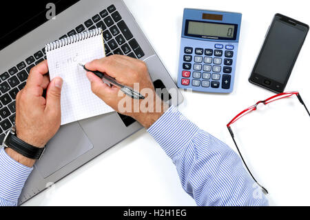 Vista dall'alto di un uomo la scrittura su un blocco note sulla scrivania in un ufficio moderno Foto Stock