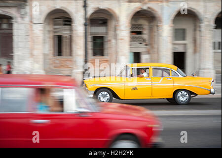 L'Avana - Giugno 13, 2011: vivacemente colorato vintage americano auto taxi condividono la strada in motion blur sul lungomare Malecon. Foto Stock