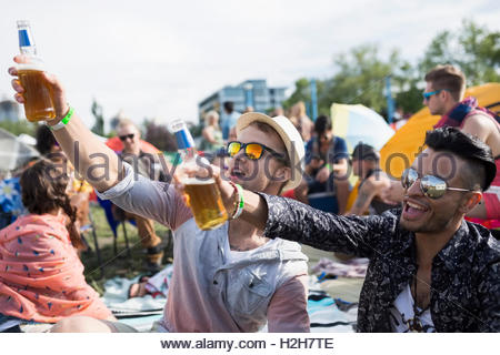I giovani uomini a bere birra rasserenante al festival musicale estivo Campeggio