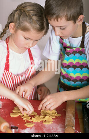 Ragazzo e una ragazza forme di taglio di un collegamento per la pasticceria biscotti Foto Stock