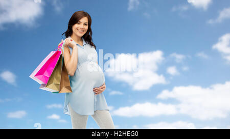 Felice donna incinta con borse per lo shopping Foto Stock