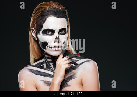Giovane donna con scheletro gotico trucco su sfondo nero Foto Stock