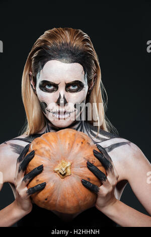 Primo piano della donna con scheletro gotico trucco tenendo la zucca su  sfondo nero Foto stock - Alamy