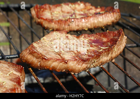 Sizzling grigliate di carni bovine bistecche grigliate con spezie preparato di cottura sulla griglia per il barbecue, close up Foto Stock