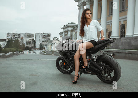 Biker ragazza scorre una motocicletta sotto la pioggia. Visuale in prima persona Foto Stock