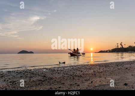 Due turisti asiatici paddeling kayak al tramonto, appena fuori dalla spiaggia in una zona molto calma il mare Foto Stock