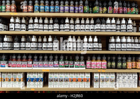 File di bottiglie di liquidi di sapori diversi per vaping e vapori sul display in un negozio Foto Stock