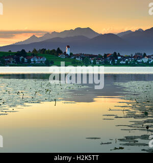 Hopfensee con village Hopfen am See, nella parte anteriore delle Alpi dell'Algovia, sunrise, Atmosfera mattutina, Algovia, Baviera, Germania Foto Stock