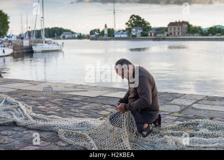Fisherman riparazione di una rete da pesca in Honfleur, in Francia, in Europa. Foto Stock