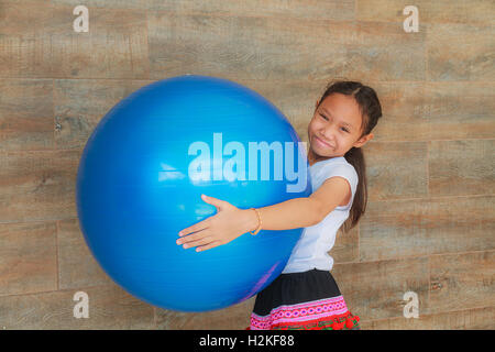 Ragazza bambino blu holding grande palla di gomma. Foto Stock