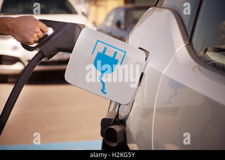 Immagine a colori di una mano di un uomo la preparazione per caricare un auto elettrica. Foto Stock