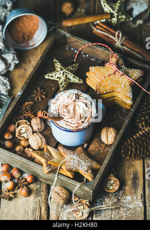 La tazza di cioccolata calda con panna montata, la polvere di cacao, cannella, gingerbread cookie, i dadi nel vassoio in legno con Natale decorat Foto Stock
