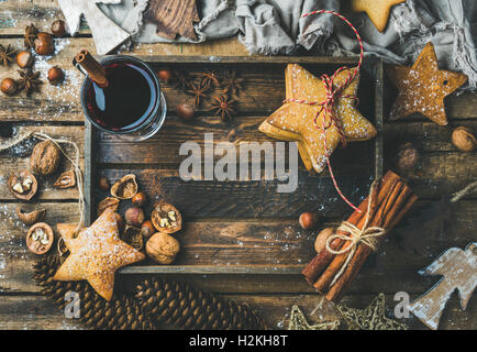 Bicchiere di vino brulé nel vassoio in legno con decorazione di Natale giocattoli, gingerbread cookies, dadi, cannella, anice, lo zucchero in polvere e Foto Stock