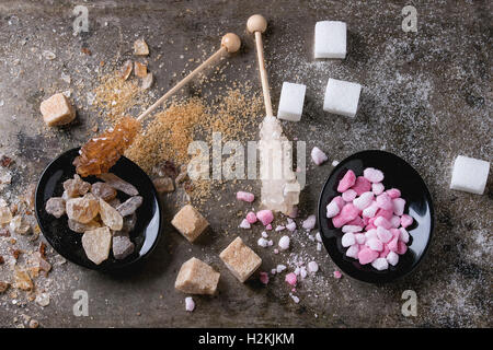 Varietà di zucchero bianco, marrone rosa granulato di frutta, cubi e cristallo su vecchio texture di sfondo di ferro. Vista dall'alto. Foto Stock