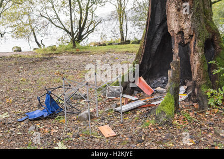 Campeggio selvaggio problemi - il comportamento antisociale e danni ambientali - sulla sponda occidentale del Loch Lomond Scozia - lettiera e detriti Albero bruciato Foto Stock