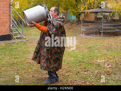 Senior uomo beve l'acqua da un grande latte-può Foto Stock