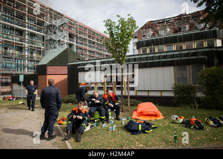 Bochum, Germania. Il 30 settembre, 2016. I vigili del fuoco di sedersi di fronte alla costruzione presso l'Ospedale Bergmannsheil a seguito di un fuoco per tutta la notte a Bochum, Germania, 30 settembre 2016. Secondo il dipartimento dei vigili del fuoco, due persone sono state uccise e almeno 16 feriti nella grande incendio presso l'ospedale. Foto: MAJA HITIJ/dpa/Alamy Live News Foto Stock