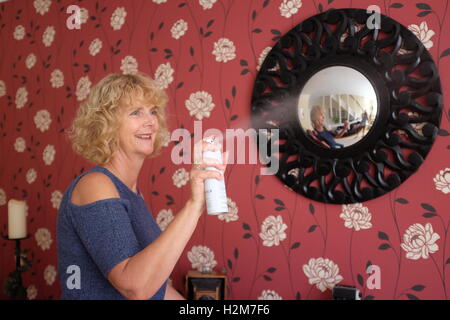 Donna fare pulizie domestiche faccende utilizzando profumatore bomboletta per aerosol a casa Foto Stock