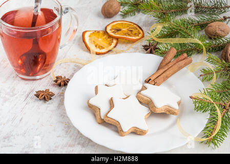 Close up di burro fatti in casa i dadi a forma di stella i biscotti con la glassa, pino, fettine di arancia, cannella, anice, noci e nastro d'oro Foto Stock