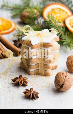 Close up di burro fatti in casa i dadi a forma di stella i biscotti con la glassa, pino, fettine di arancia, cannella, anice, noci e nastro d'oro Foto Stock