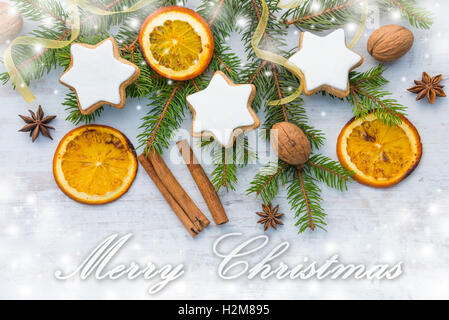 Decorazione di natale su uno sfondo di legno. Vista superiore del burro fatti in casa i dadi a forma di stella i biscotti con la glassa, pino, arancione Foto Stock