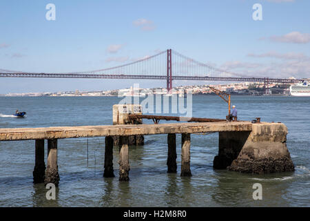 La pesca dal molo e il Ponte 25 de Abril sospensione ponte Lisbona Foto Stock