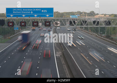 Il traffico del tramonto M25 rivolta verso Nord Est la congiunzione 17 con smart autostrada la limitazione di velocità del gantry Foto Stock