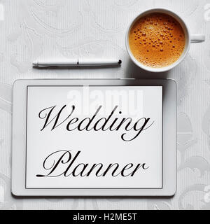 Alta angolazione della tazza di caffè, una penna digitale e un computer tablet con il testo wedding planner nel suo schermo disposto su un fl Foto Stock