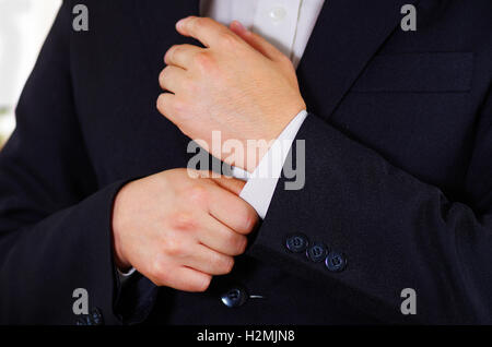 Closeup uomo braccio indossare tuta, regolazione gemelli usando le mani, gli uomini di vestirsi concept Foto Stock