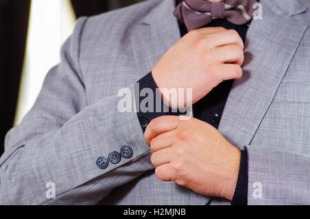 Closeup uomo braccio indossare tuta, regolazione gemelli usando le mani, gli uomini di vestirsi concept Foto Stock