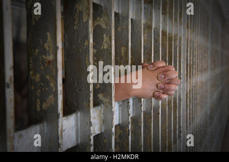 Le mani del prigioniero rinserrata in appoggio sulle barre di prigione Foto Stock