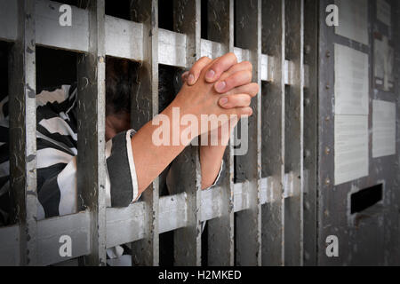 Prigioniero dietro le sbarre con le mani chiuse al di fuori del bar Foto Stock