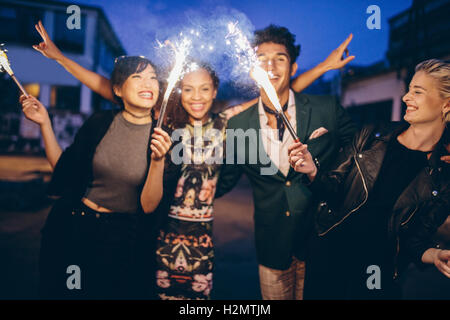 Gruppo di amici azienda botti fuori sulla strada di notte. Giovani uomini e donne aventi festa notturna con botti. Foto Stock