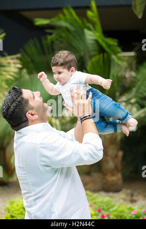 Uomo felice sollevando il suo figlio fino all'aperto Foto Stock