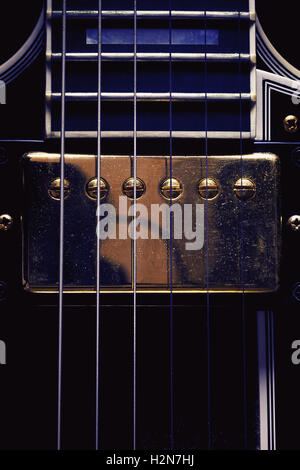 Parte di una chitarra elettrica, closeup vista sul doppio pickup con superficie impolverata. Foto Stock