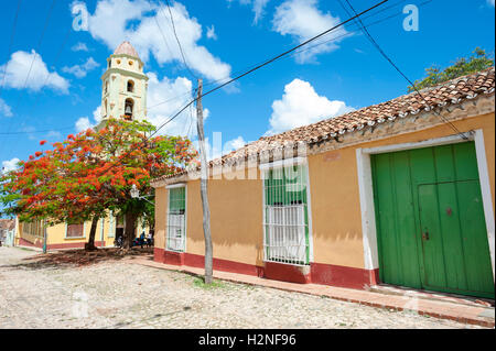 Vista panoramica della tradizionale architettura coloniale con un tropicale flame tree e un campanile della chiesa in Trinidad, Cuba Foto Stock