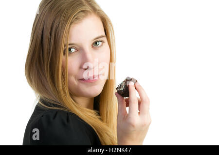 Un attraente donna bionda di mangiare una torta al cioccolato Foto Stock