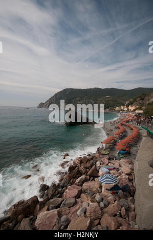 La spiaggia e il percorso costiero a Monterosso Al Mare, mostrando un sacco di ombrelli eretto sulla sabbia, Cinque Terre, Italia, Settembre Foto Stock