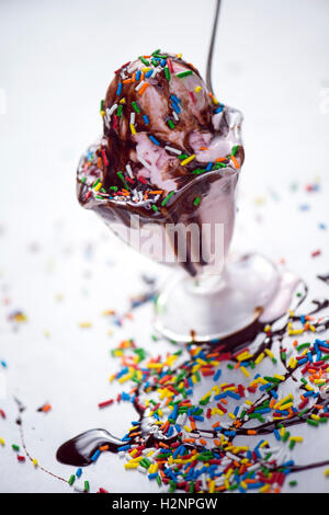 Delizioso gelato alla fragola in un bicchiere con un pizzico e salsa al cioccolato versato su di esso Foto Stock