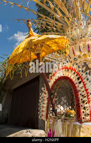 Indonesia, Bali, Putung, Kuningan festival, penjor decorazioni con offrendo all'interno ombreggiato da un parasole Foto Stock