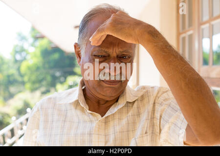 Closeup ritratto, imbronciato anziano pensionato, abbattuto cupo, mano appoggiata sulla testa, isolato al di fuori all'aperto home contesto Foto Stock