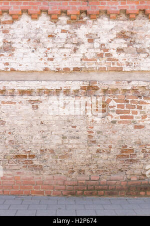 Rotture di vecchia muratura muro dal rosso bianco di mattoni con intonaco danneggiato e pavimentazione stradale texture di sfondo Foto Stock