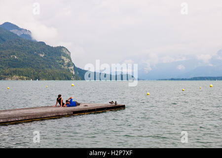 Sankt Gilgen, Austria - Luglio 5, 2013: una giovane coppia rilassante su un molo in legno sul lago Wolfgangsee nelle Alpi austriache. Foto Stock