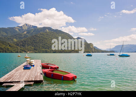 Pier e rosso barche sul lago alpino Wolfgangsee, Austria Foto Stock