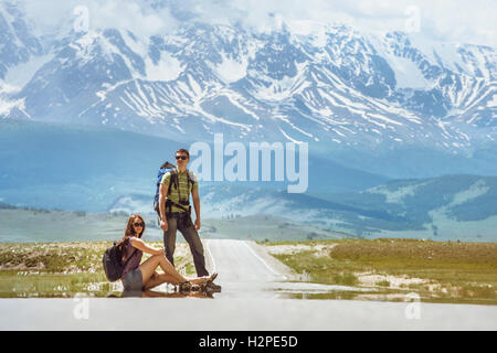 Coppia di viaggiatori rimane sulla strada delle bellissime montagne Foto Stock