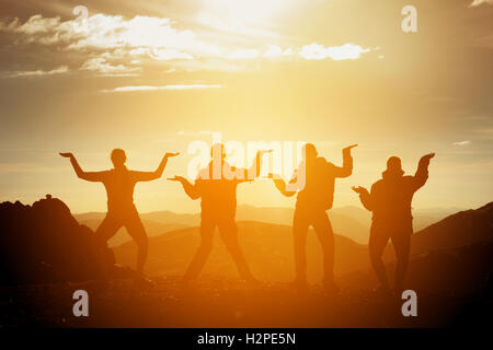Gruppo di happy amici divertendosi su sfondo al tramonto Foto Stock