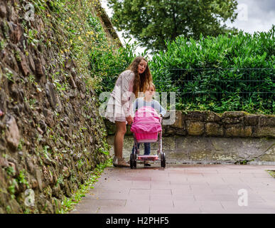 Due sorelle con babycarrier per bambole, all'aperto. Concetto di infanzia Foto Stock